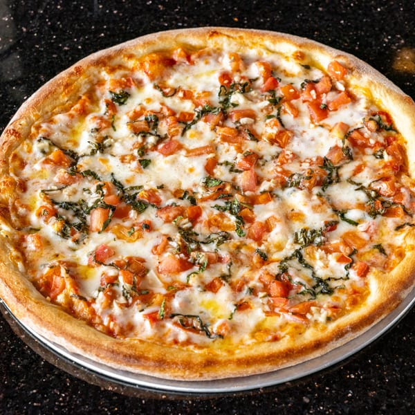 Grande Pizza's Margherita pizza, topped with diced tomatoes, fresh basil, and melted mozzarella cheese.