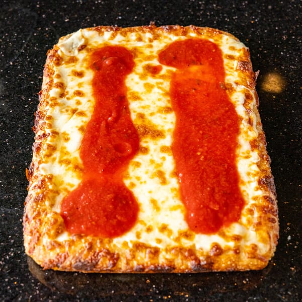Grande Pizza's rectangular Detroit-style pizza with melted cheese and two stripes of red sauce.